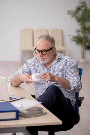 Foto de Viejo empleado bebiendo café durante el descanso - Imagen libre de derechos