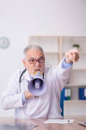 Foto de Viejo doctor sosteniendo megáfono en la clínica - Imagen libre de derechos