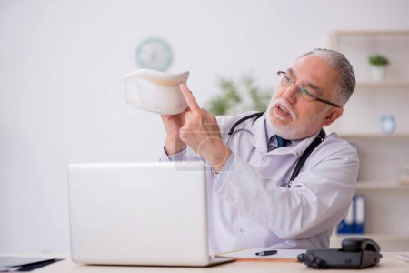 Photo for Old doctor holding neck brace in the clinic - Royalty Free Image