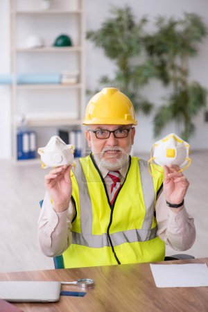 Photo for Old architect holding respirator in the office - Royalty Free Image