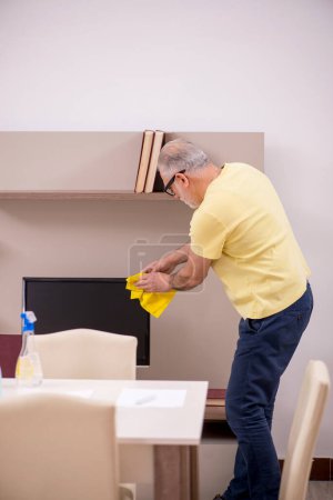 Téléchargez les photos : Le vieil homme nettoie la maison - en image libre de droit