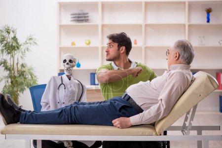 Foto de Viejo paciente visitando esqueleto médico - Imagen libre de derechos
