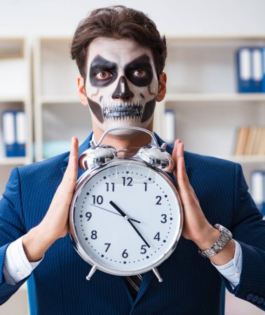 Téléchargez les photos : Homme d'affaires avec masque effrayant travaillant dans le bureau - en image libre de droit