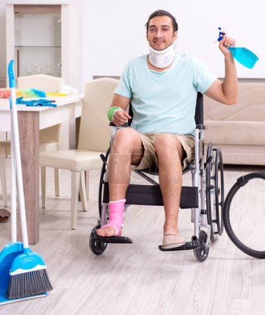 Foto de El joven en silla de ruedas limpiando la casa - Imagen libre de derechos