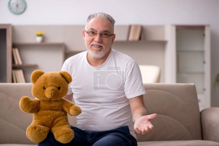 Foto de Viejo con oso de juguete en la casa - Imagen libre de derechos