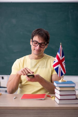Téléchargez les photos : Jeune professeur d'anglais assis dans la salle de classe - en image libre de droit
