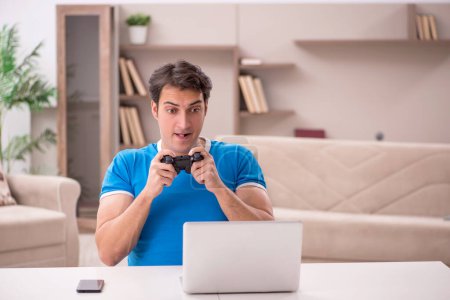 Foto de Joven estudiante masculino jugando videojuegos en casa - Imagen libre de derechos