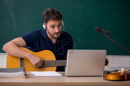 Photo for Young music teacher sitting in the classroom - Royalty Free Image
