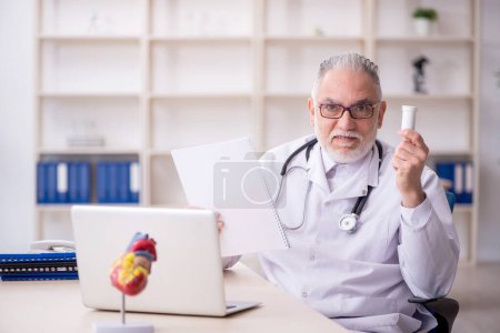 Photo for Old male doctor suggesting pills at the hospital - Royalty Free Image