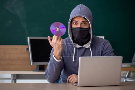 Téléchargez les photos : Jeune hacker assis dans la salle de classe - en image libre de droit