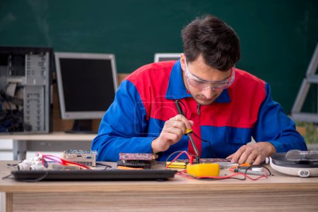 Téléchargez les photos : Jeune réparateur réparer des ordinateurs dans la salle de classe - en image libre de droit