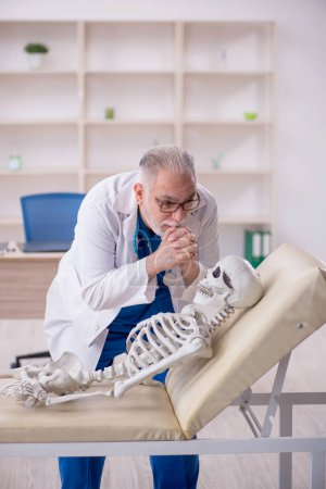 Téléchargez les photos : Old male doctor and skeleton patient at the hospital - en image libre de droit