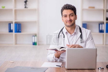 Photo for Young doctor reading book in the clinic - Royalty Free Image
