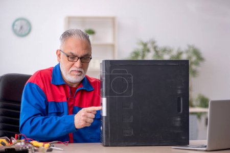 Foto de Viejo reparador reparando computadora en el laboratorio - Imagen libre de derechos