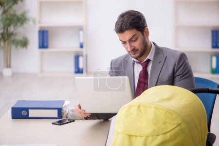 Photo for Young employee looking after newborn in the office - Royalty Free Image