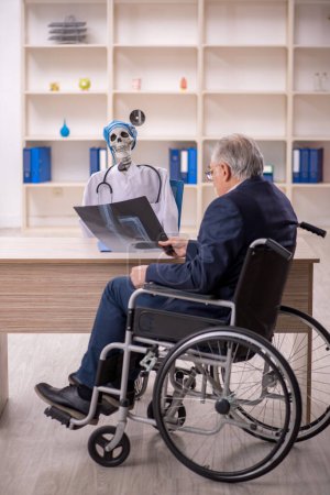 Téléchargez les photos : Vieux patient masculin en fauteuil roulant visitant diable médecin - en image libre de droit
