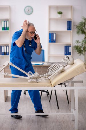 Foto de Viejo doctor examinando esqueleto en el hospital - Imagen libre de derechos