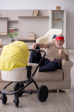 Foto de Hombre anciano que cuida del recién nacido en casa - Imagen libre de derechos