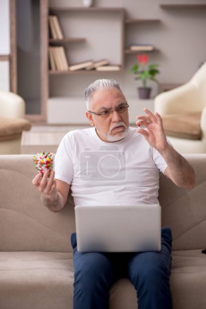 Foto de Viejo sosteniendo vidrio con pastillas en casa - Imagen libre de derechos