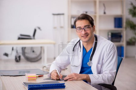 Téléchargez les photos : Jeune homme médecin travaillant à l'hôpital - en image libre de droit