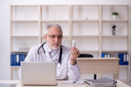 Téléchargez les photos : Vieux médecin masculin suggérant des pilules à l'hôpital - en image libre de droit