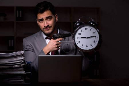 Téléchargez les photos : Young employee working late at workplace - en image libre de droit