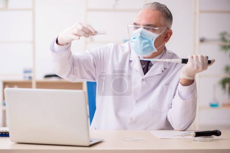 Foto de Antiguo químico trabajando en el laboratorio durante una pandemia - Imagen libre de derechos