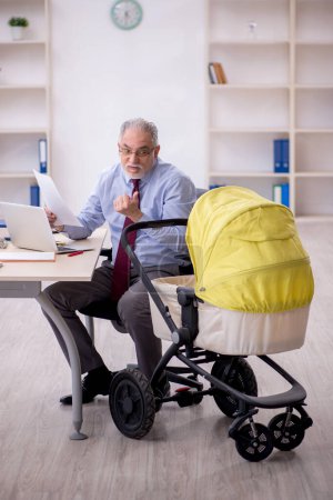Foto de Un viejo empleado de negocios que cuida a un recién nacido en la oficina - Imagen libre de derechos
