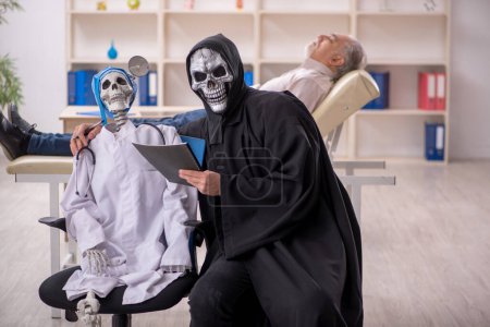 Foto de Dos doctores del diablo examinando paciente viejo - Imagen libre de derechos