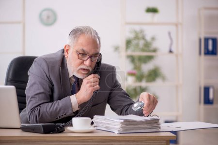 Téléchargez les photos : Vieil homme d'affaires employé travaillant sur le lieu de travail - en image libre de droit
