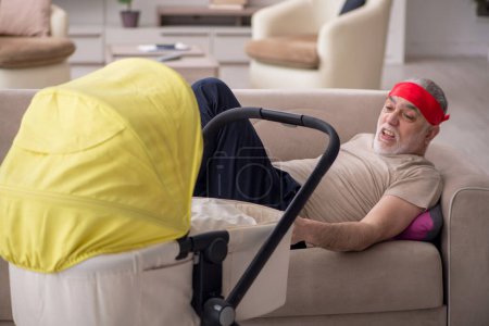Téléchargez les photos : Homme âgé s'occupant du nouveau-né à la maison - en image libre de droit