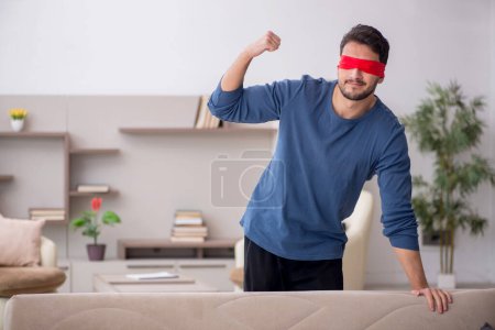 Photo for Blindfolded young man seeking at home - Royalty Free Image