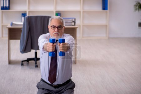Foto de Viejo empleado haciendo ejercicios deportivos durante el descanso - Imagen libre de derechos