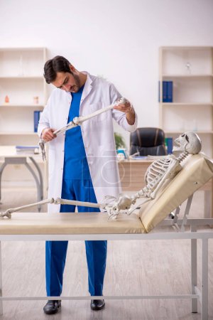 Foto de Joven doctor con esqueleto en el hospital - Imagen libre de derechos