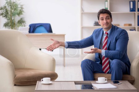 Téléchargez les photos : Jeune homme d'affaires assis sur le lieu de travail - en image libre de droit