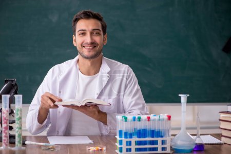 Photo for Young chemist in front of green board - Royalty Free Image