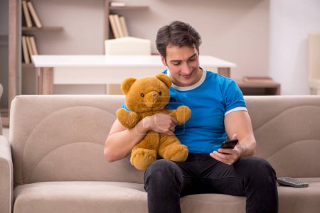 Photo for Young man sitting with bear toy at home - Royalty Free Image