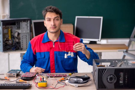 Foto de Joven reparador reparando computadoras en el aula - Imagen libre de derechos