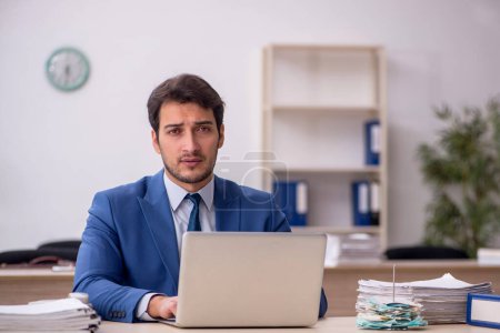 Téléchargez les photos : Jeune employé masculin assis sur le lieu de travail - en image libre de droit