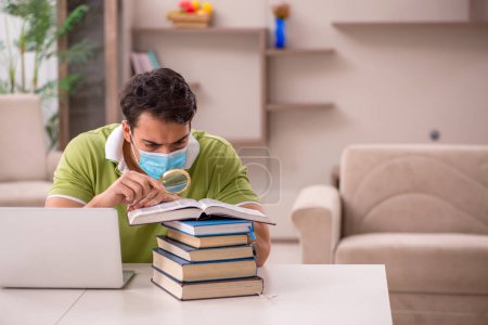 Téléchargez les photos : Jeune étudiant se préparant aux examens à domicile pendant la pandémie - en image libre de droit