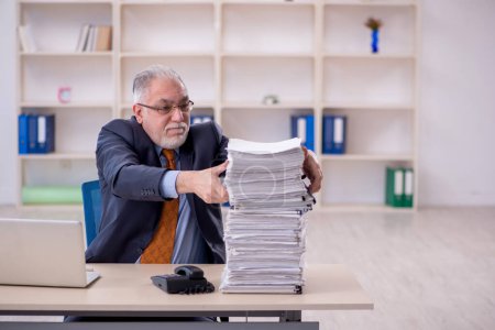 Téléchargez les photos : Old male employee and too much work at workplace - en image libre de droit