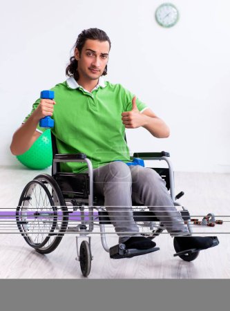 Téléchargez les photos : Le jeune homme en fauteuil roulant faisant des exercices à l'intérieur - en image libre de droit
