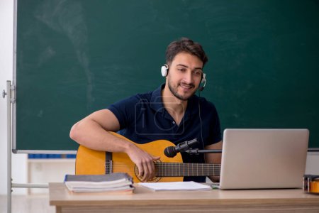Foto de Joven profesor de música sentado en el aula - Imagen libre de derechos