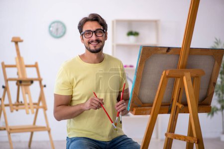 Téléchargez les photos : Jeune peintre masculin appréciant la peinture à la maison - en image libre de droit