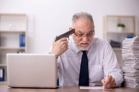 Photo for Old employee holding gun at workplace - Royalty Free Image