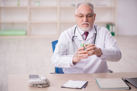 Téléchargez les photos : Vieux médecin suggérant des pilules à la clinique - en image libre de droit
