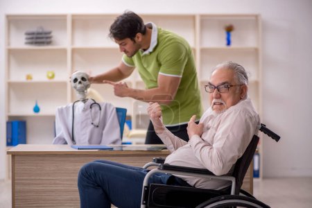 Téléchargez les photos : Vieux patient masculin en fauteuil roulant visitant squelette médecin - en image libre de droit