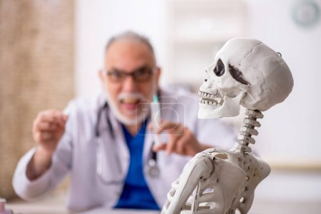 Foto de Viejo doctor examinando esqueleto en el hospital - Imagen libre de derechos
