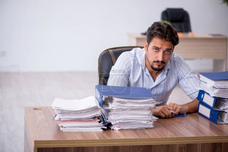 Téléchargez les photos : Jeune homme d'affaires employé mécontent du travail excessif sur le lieu de travail - en image libre de droit