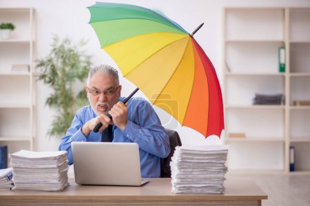 Photo for Old employee holding an umbrella at workplace - Royalty Free Image